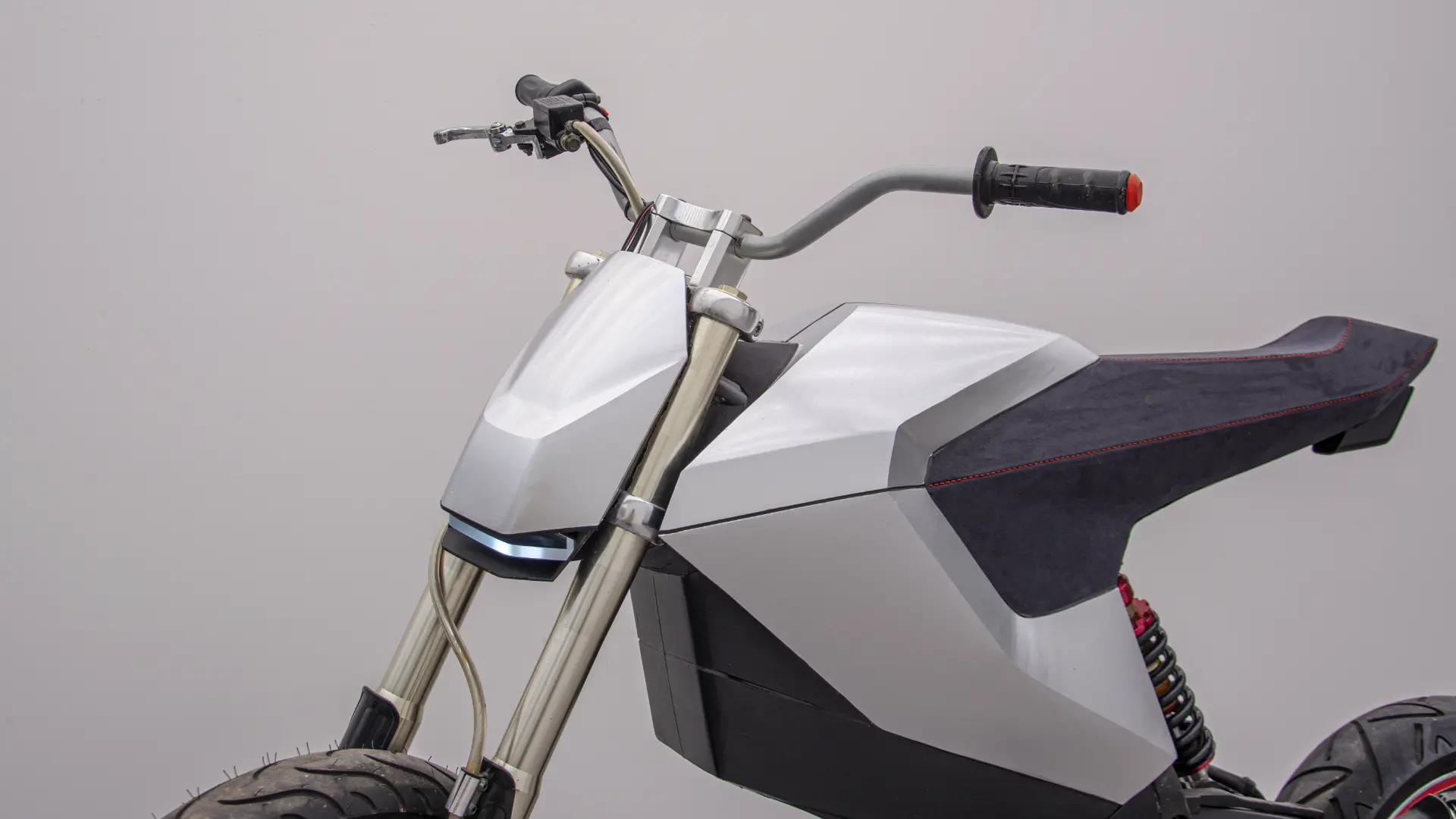 Side profile of the E-moto prototype showing the seat, bodywork and front end